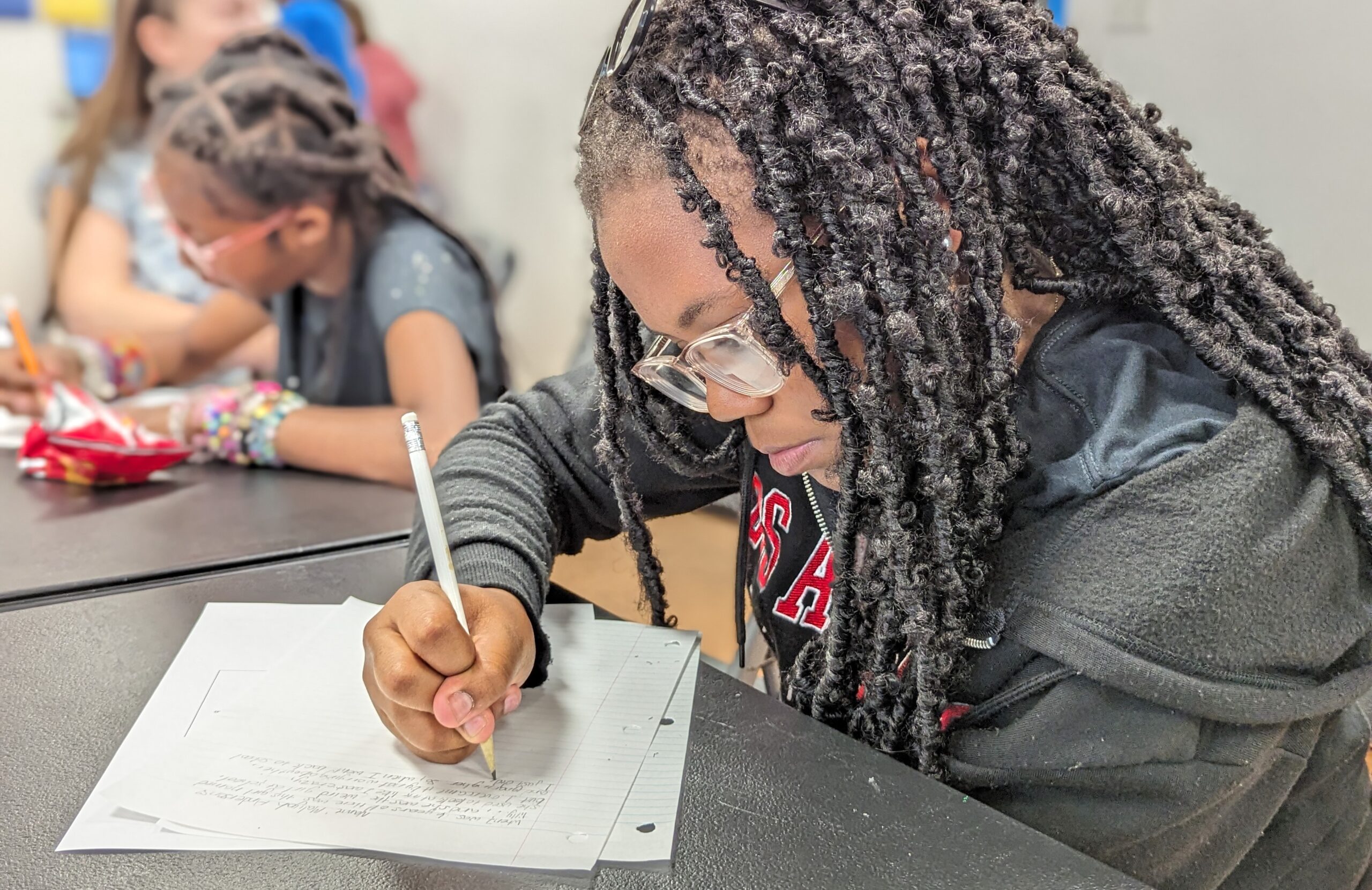 A young person focuses diligently while writing.