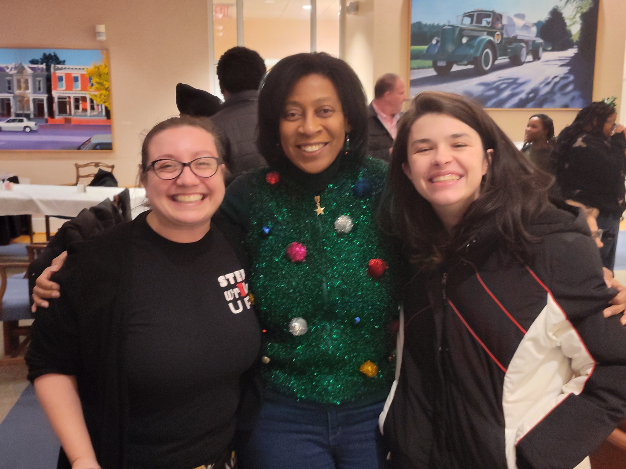 An adult Three adults pose for a group shot . They are smiling